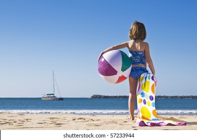 Young Child Standing With Beachball And Towel Ready To Play.