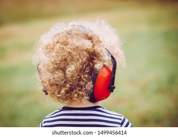 Young Child Wearing Noise Blocking Headphones At Outdoor Concert, Preventing Hearing Loss At Young Age Concept.