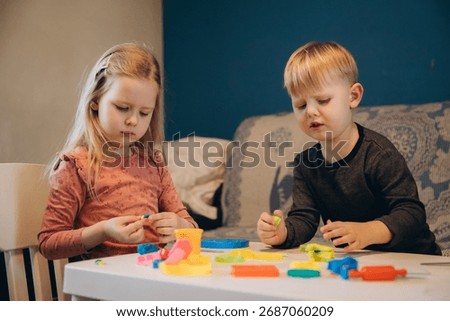 Young children developing creativity and fine motor skills, creating colorful shapes with play-doh tools at a table