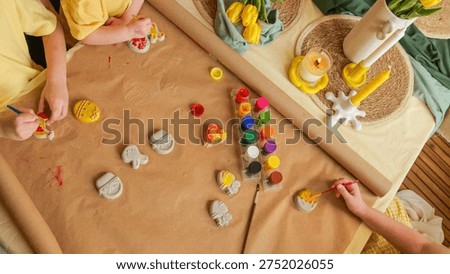 Young children are engaged in a creative Easter craft activity, painting ceramic figures with colorful paints on a craft table