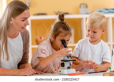 Young Children Are Looking Through The Microscope While Doing A Science Preschool Project. STEM In Education Concept.