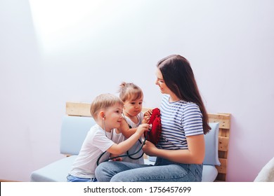 Young Children Play Doctor With Mom, Listen To The Heart With A Stethoscope.