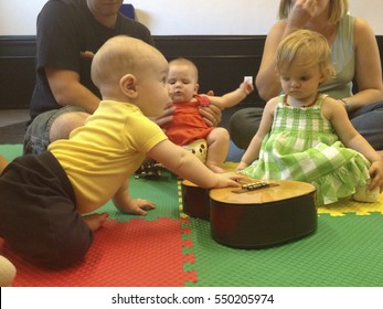 Young children are playing with a guitar in a music class for toddlers as parents watch. For editorial use: Location: Mesa, Arizona, USA. Date: December 15, 2012.