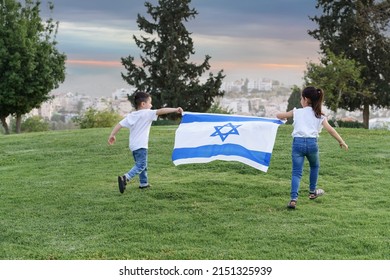 Young children running with Israeli flag. Rear view little girl and boy running with Israel flag up a hill in the sunset - Shutterstock ID 2151325939