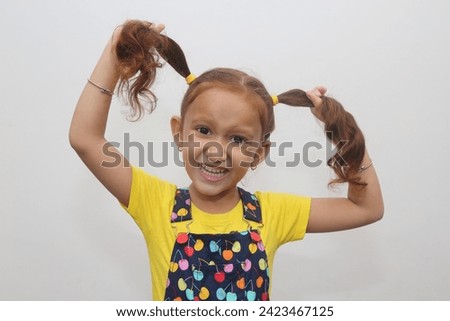 Young child's naughty expression in white background. Beautiful young girl with brown hair. Expression stock photograph.