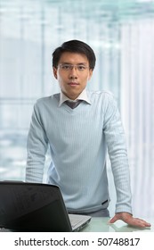 Young Chinese Businessman Standing In His Office