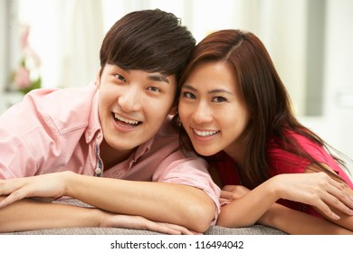 Young Chinese Couple Relaxing On Sofa At Home