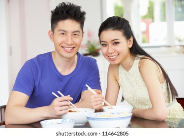 Young Chinese Couple Sitting At Home Eating Meal