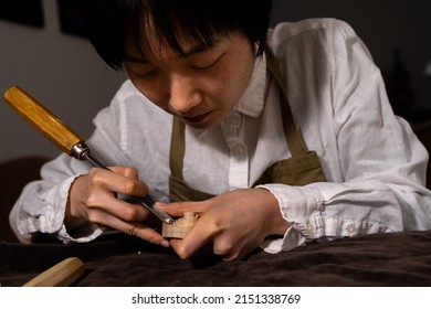 young Chinese female violin maker working with gouge to making a new violin in her workshop - Powered by Shutterstock