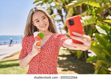 Young Chinese Girl Eating Ice Cream Make Selfie By The Smartphone At The Promenade.