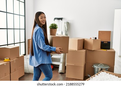 Young Chinese Girl Smiling Happy Holding Cardboard Box At New Home