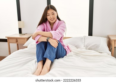 Young Chinese Girl Smiling Happy Sitting On The Bed At Bedroom.