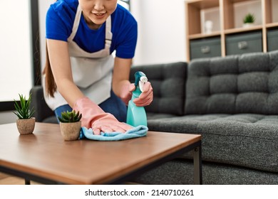 Young chinese housewife cleaning table using diffuser and rag at home. - Shutterstock ID 2140710261
