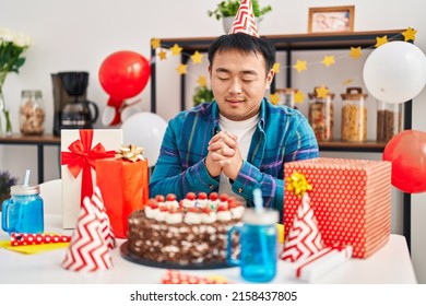 Young Chinese Man Celebrating Birthday Sitting On Table At Home