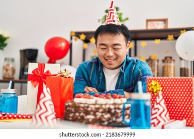 Young Chinese Man Celebrating Birthday Sitting On Table At Home