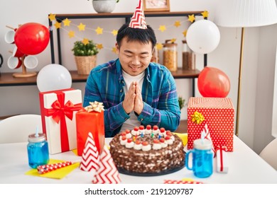 Young Chinese Man Celebrating Birthday Sitting On Table At Home