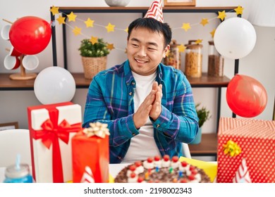 Young Chinese Man Celebrating Birthday Sitting On Table At Home