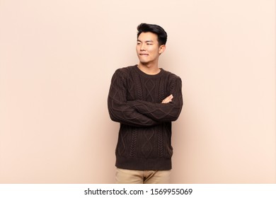 young chinese man doubting thinking  biting lip   feeling insecure   nervous  looking to copy space the side against flat color wall