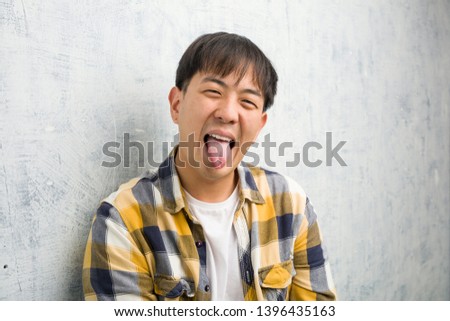 Young chinese man face closeup funnny and friendly showing tongue