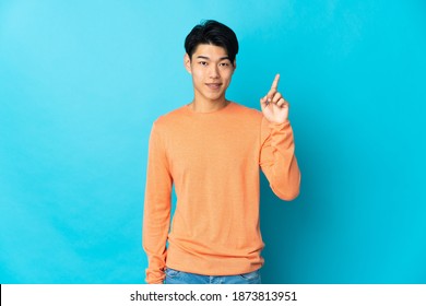 Young Chinese Man Isolated On Blue Background Showing And Lifting A Finger In Sign Of The Best