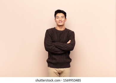 Young Chinese Man Looking Like A Happy, Proud And Satisfied Achiever Smiling With Arms Crossed Against Flat Color Wall