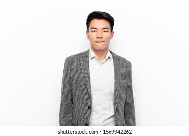 young chinese man looking puzzled   confused  biting lip and nervous gesture  not knowing the answer to the problem against flat color wall