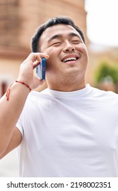 Young Chinese Man Smiling Confident Talking On The Smartphone At Street