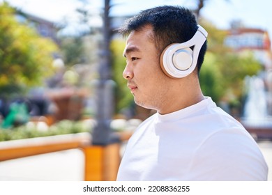 Young Chinese Man Smiling Confident Listening To Music At Park