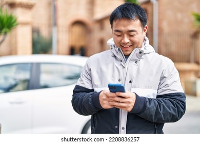 Young Chinese Man Smiling Confident Using Smartphone At Street