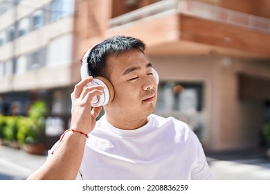 Young Chinese Man Smiling Confident Listening To Music At Street