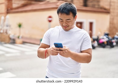 Young Chinese Man Smiling Confident Using Smartphone At Street