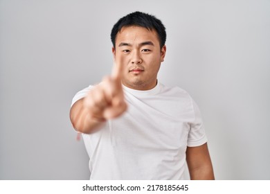 Young Chinese Man Standing Over White Background Pointing With Finger Up And Angry Expression, Showing No Gesture 