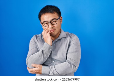 Young Chinese Man Standing Over Blue Background Thinking Looking Tired And Bored With Depression Problems With Crossed Arms. 