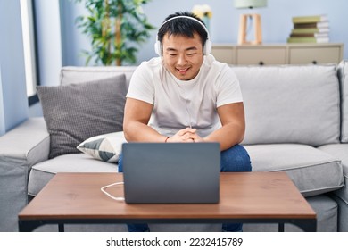 Young chinese man using laptop at home looking positive and happy standing and smiling with a confident smile showing teeth  - Shutterstock ID 2232415789
