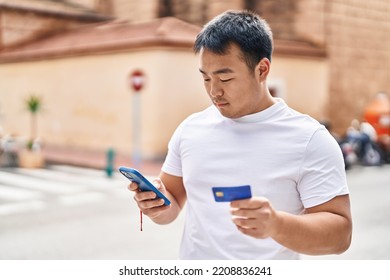 Young Chinese Man Using Smartphone And Credit Card At Street