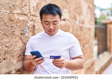 Young Chinese Man Using Smartphone And Credit Card At Street