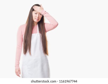 Young Chinese Shop Owner Woman Over Isolated Background Wearing White Apron Stressed With Hand On Head, Shocked With Shame And Surprise Face, Angry And Frustrated. Fear And Upset For Mistake.