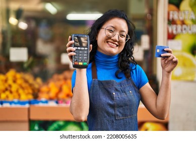 Young Chinese Woman Employee Holding Data Phone And Credit Card At Fruit Store