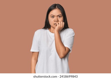 Young chinese woman isolated biting fingernails, nervous and very anxious.