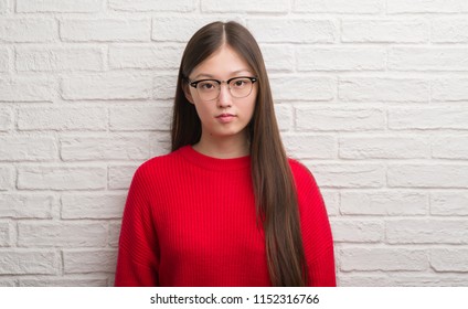 Young Chinese Woman Over Brick Wall With A Confident Expression On Smart Face Thinking Serious