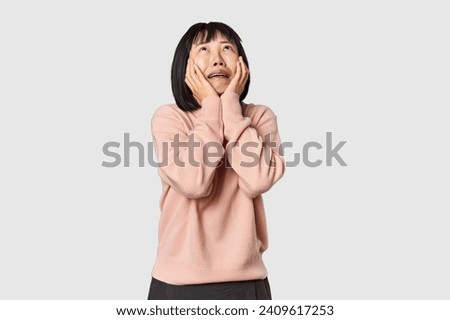 Young Chinese woman posing on studio background whining and crying disconsolately.