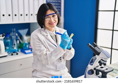 Young Chinese Woman Scientist Writing On Test Tube At Laboratory