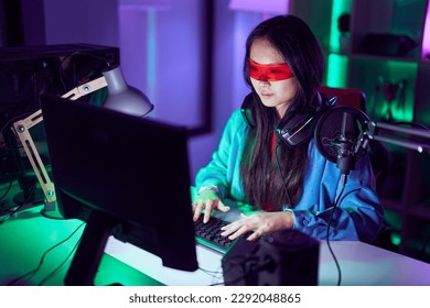 Young chinese woman streamer playing video game using virtual reality glasses at gaming room - Powered by Shutterstock