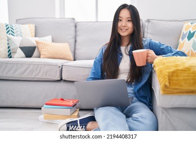 Young Chinese Woman Using Laptop Drinking Coffee At Home