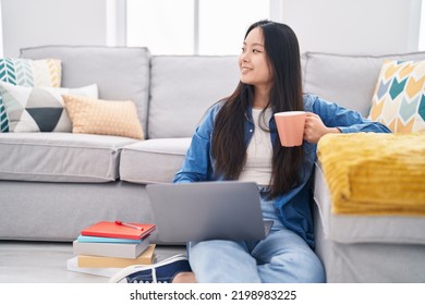 Young Chinese Woman Using Laptop Drinking Coffee At Home