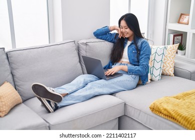 Young Chinese Woman Using Laptop Sitting On Sofa At Home