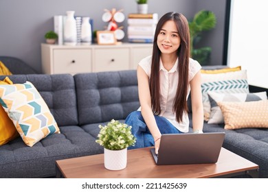 Young Chinese Woman Using Laptop Sitting On Sofa At Home