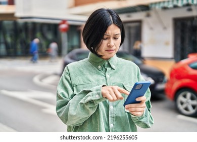 Young chinese woman using smartphone with serious expression at street - Shutterstock ID 2196255605
