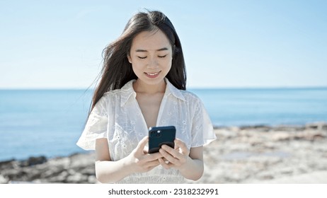 Young chinese woman using smartphone smiling at seaside - Powered by Shutterstock