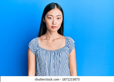 Young Chinese Woman Wearing Casual Striped T-shirt Relaxed With Serious Expression On Face. Simple And Natural Looking At The Camera. 